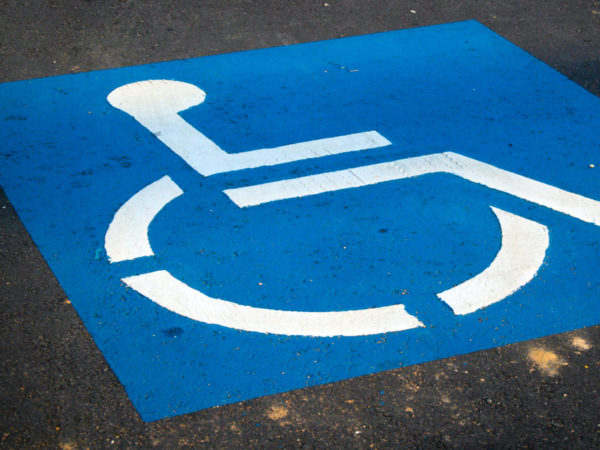 Blue and white accessibility symbol painted on asphalt