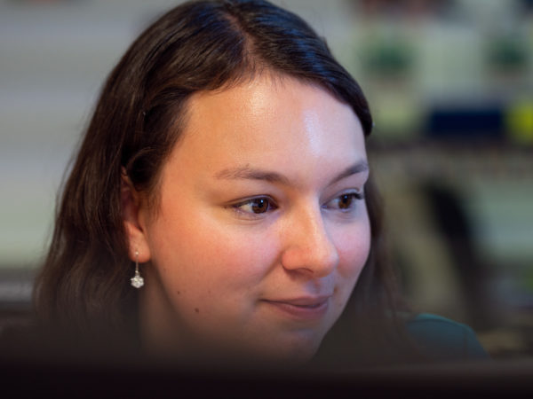 A young woman looking at a computer and smiling