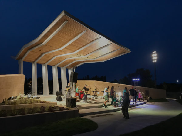 Evening view of a modern amphitheater with people playing instruments