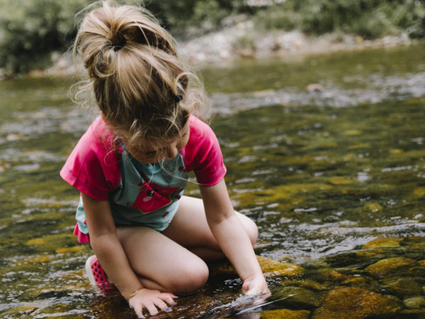 A young girl playing in a shallow stream