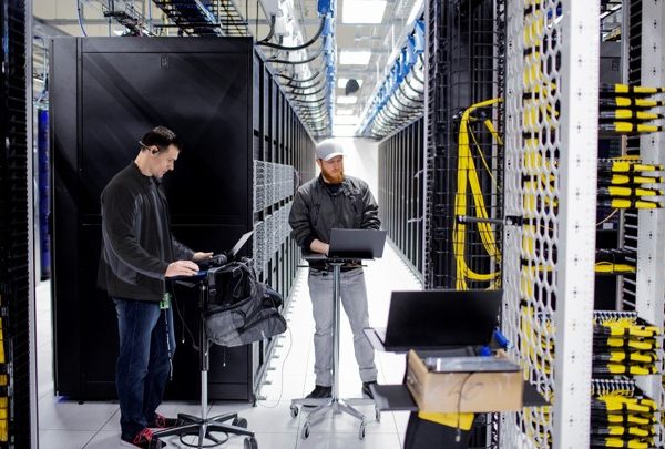Dos hombres trabajando en la sala de servidores de un centro de datos