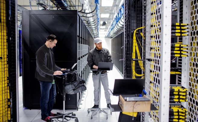 Dua pria yang bekerja di ruang server pusat data