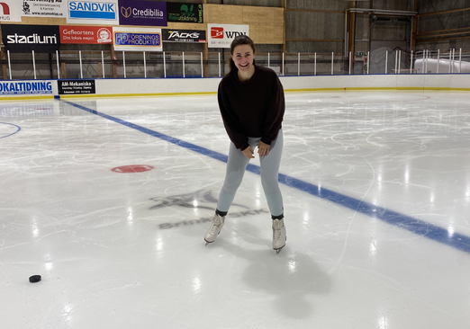 Emma en patines en una pista de hielo con un disco de hockey