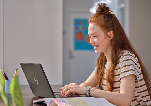 Seorang pelajar wanita muda bekerja di komputer