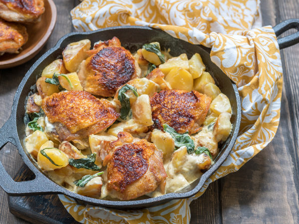 An iron skillet with a delicious looking chicken and potato dish