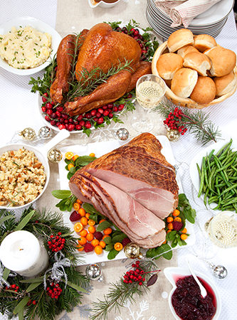 A table with Christmas dinner of turkey, ham, and potatoes