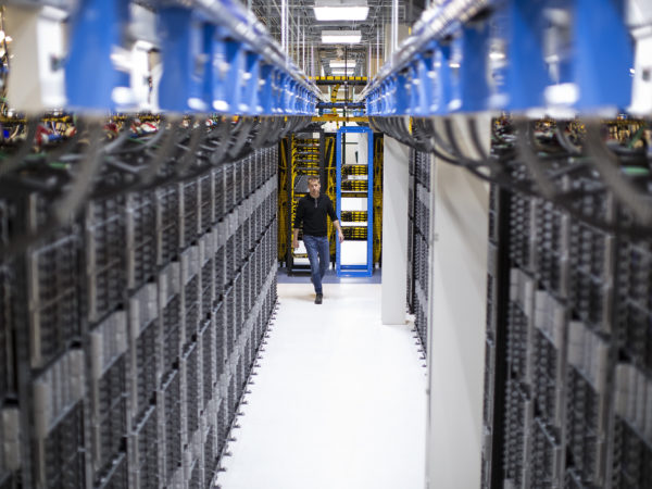 Hombre caminando por los pasillos de servidores en un centro de datos