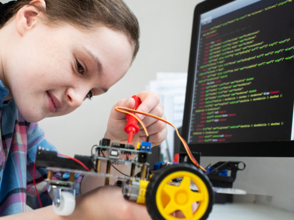 A young female student building a robot