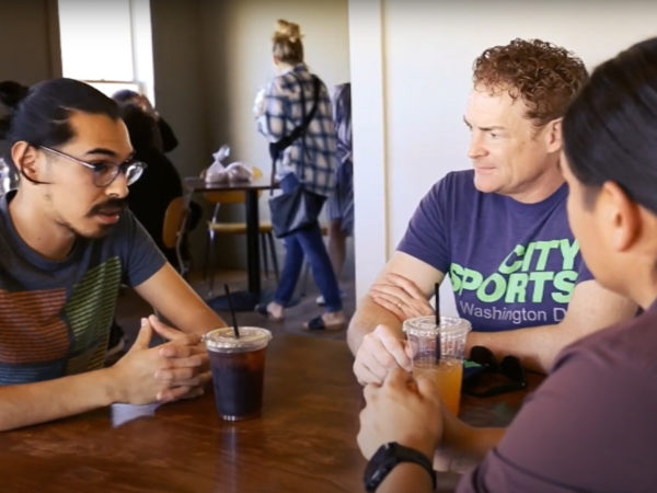 Tre personer sidder i samtale omkring et bord i en kaffebar