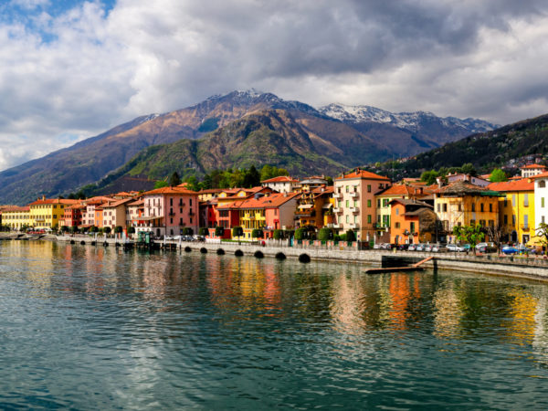 View over water of small Italian buildings with mountains in the distance