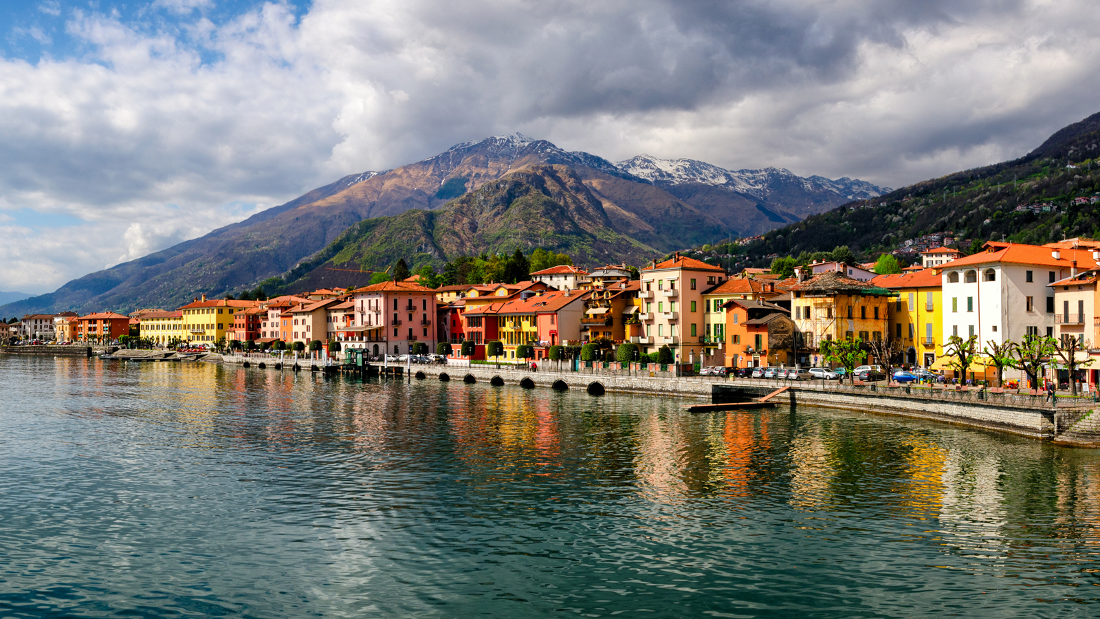 View over water of small Italian buildings with mountains in the distance