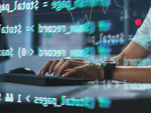 Ręce na klawiaturze pracujące z kodem i cyberbezpieczeństwem
