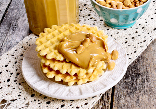 a stack of waffles on a plate with peanut butter on top