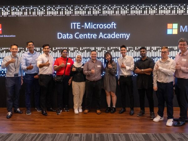 مجموعة من الأشخاص يقفون ويبتسمون أمام لافتة تظهر أكاديمية مركز البيانات ITE_Microsoft