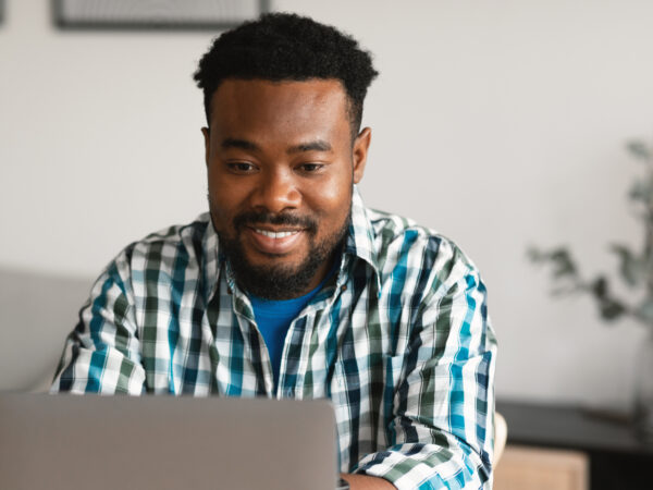 Nuori musta mies työskentelee tietokoneella