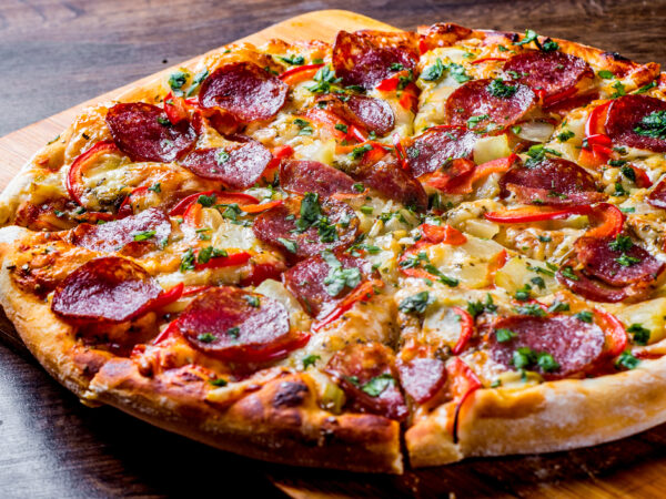 Pepperoni Pizza met Mozzarella kaas, salami, peper. Kruiden en verse basilicum. Italiaanse pizza op houten tafelachtergrond