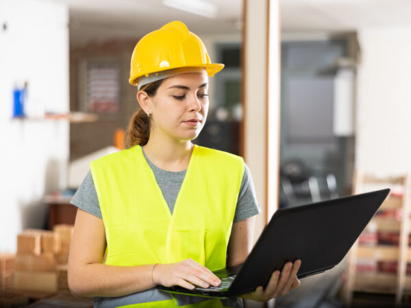 A young female construction worker using a laptop