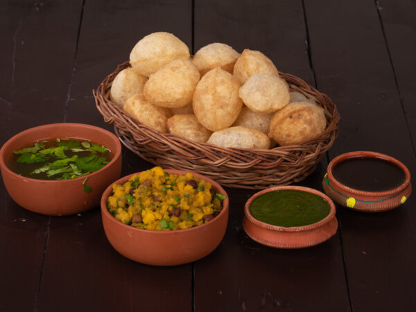 Paani puri, an Indian snack, in a bowl with dipping sauces on the side