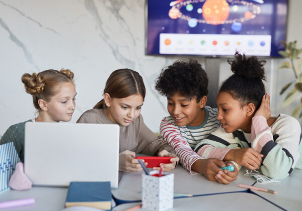 Four kids looking at a cell phone