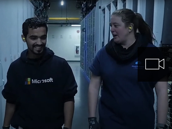 Two people walking down a server hall in a datacenter