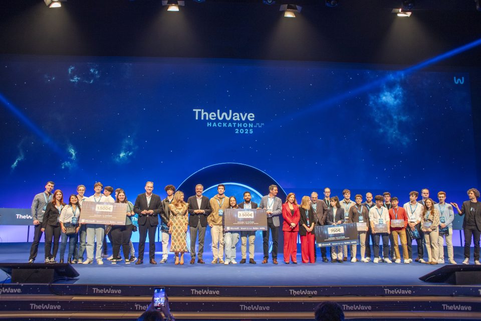 A large group of people standing on a stage at the Wave Hackathon