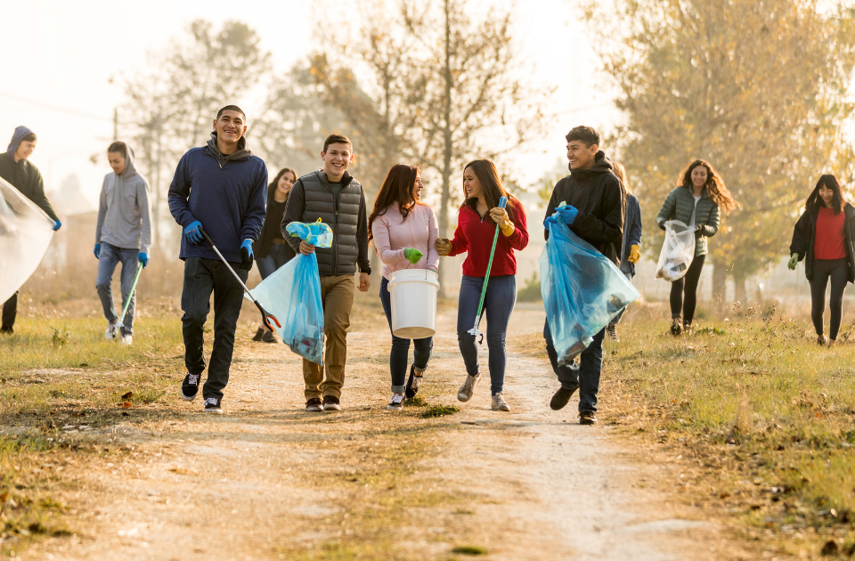 A group of young people picking up trash in a nature area