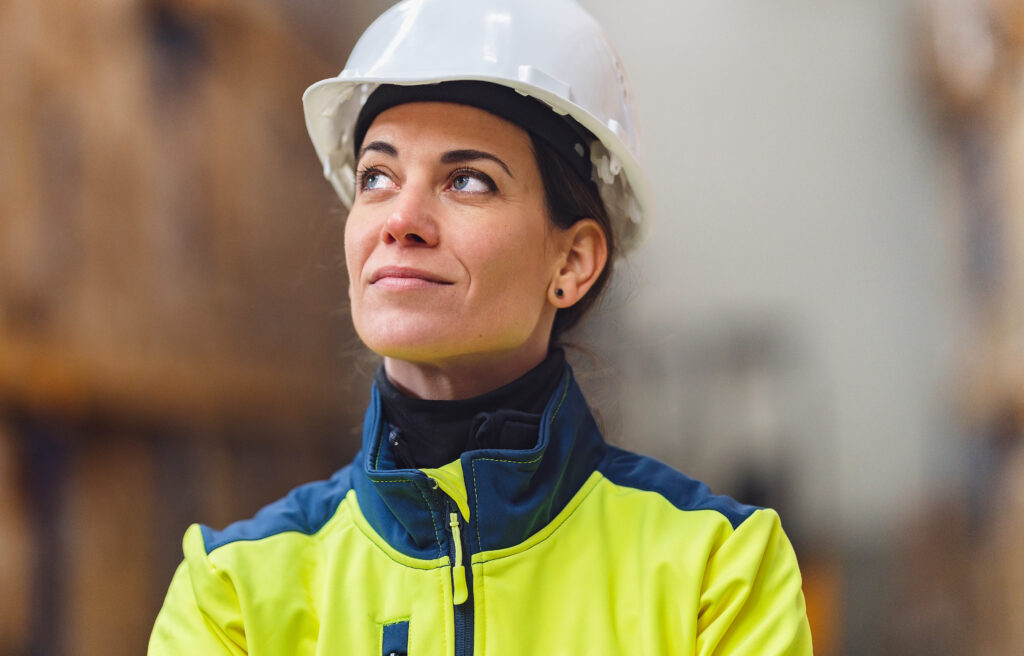 A woman wearing a construction helmet and yellow jacket