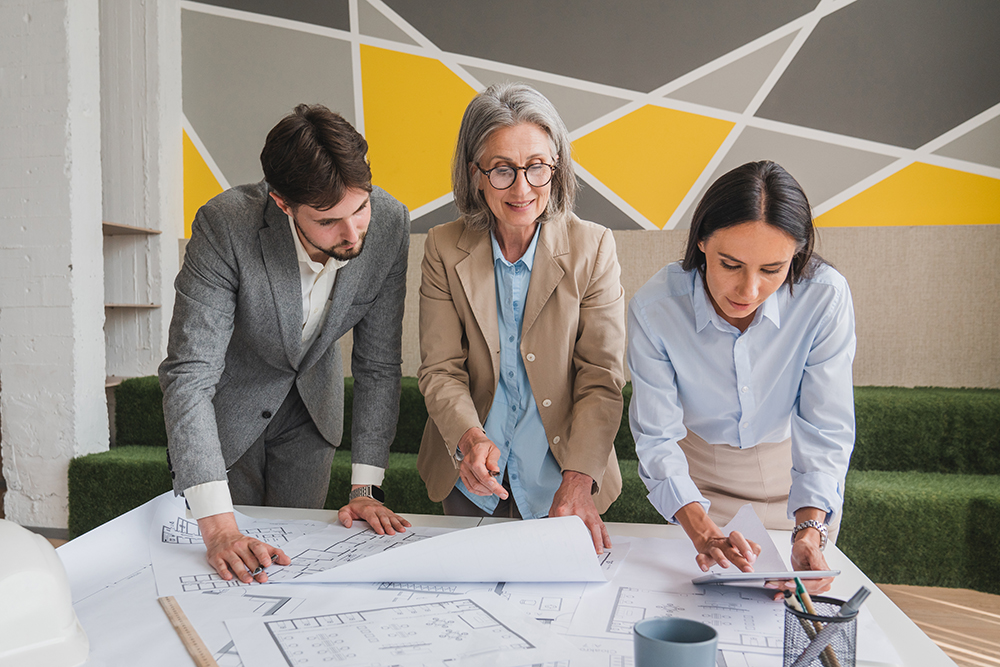 Three people looking at architectural drawings