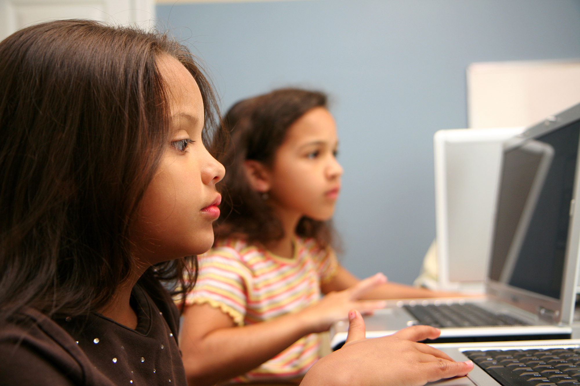 Two young girls on computers in a workshop