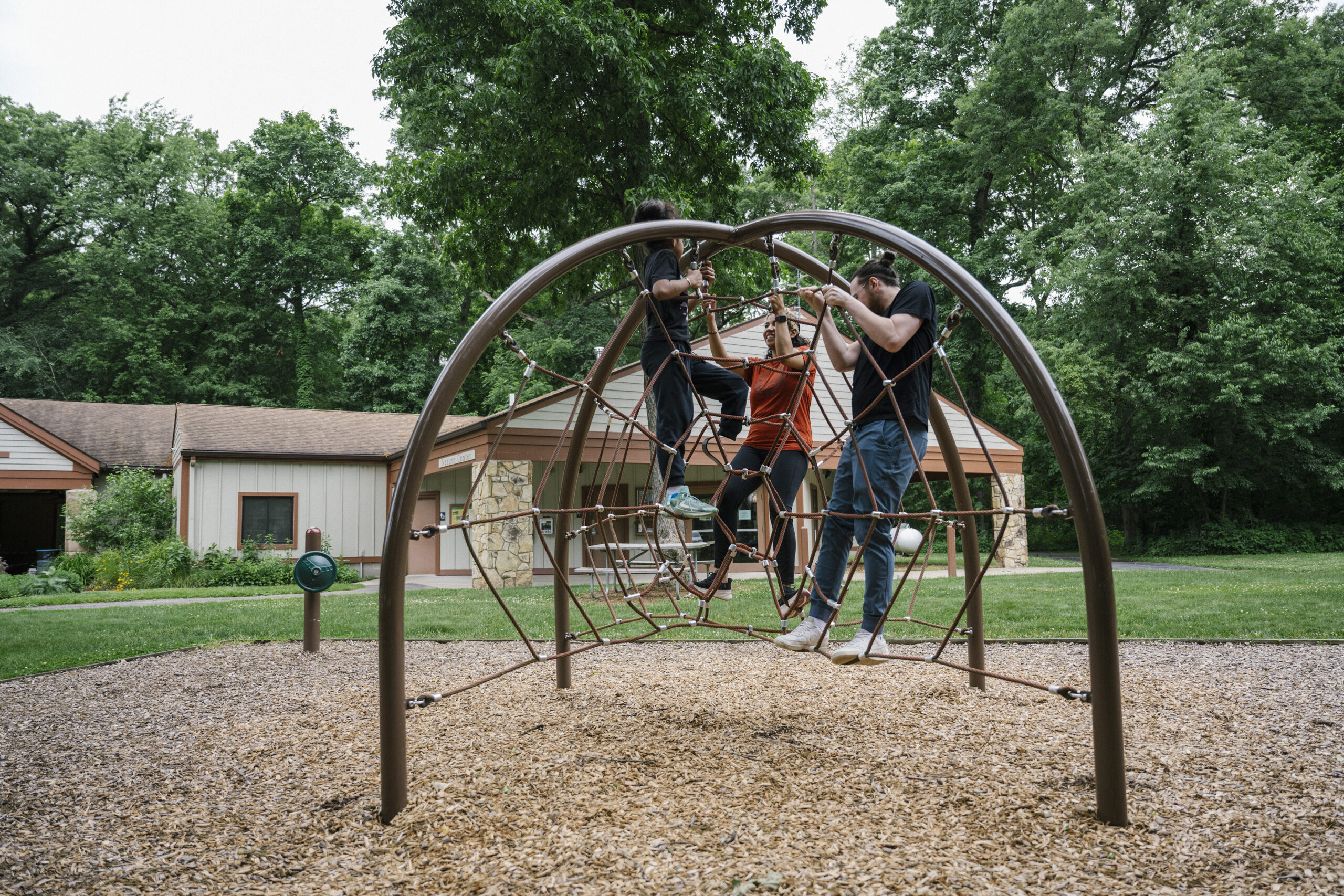 Three people on a jungle gym at a public park